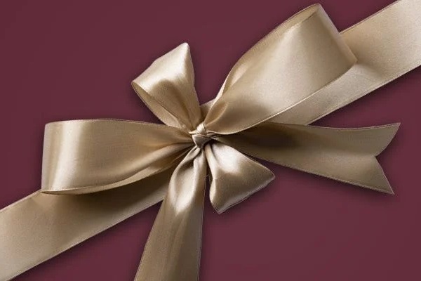 Ein goldfarbener Satinbogen befindet sich auf einem tief roten Hintergrund. Der Bogen hat mehrere Schlaufen und eine zentrale Knotenmitte.