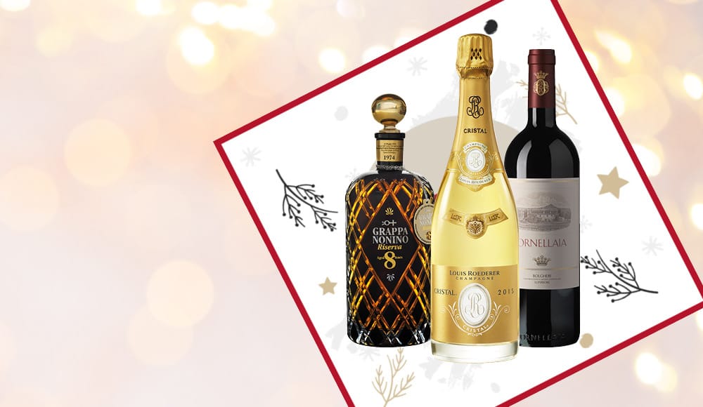Ein Grappa, ein Champagner und ein Rotwein sind auf einem festlichen Hintergrund mit unklaren Lichtern und weihnachtlichen Motiven angeordnet. Sie erscheinen elegant und ansprechend.