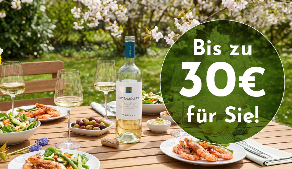 Ein schön gedeckter Tisch im Freien mit weißen Weingläsern, einer Flasche COSTAMOLINO-Wein und verschiedenen Gerichten, darunter Salate und Garnelen. Im Hintergrund blühen Bäume. Text: -Bis zu 30€ für Sie!-