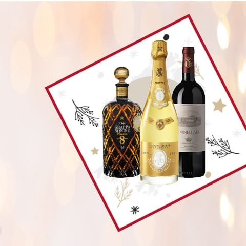 Eine Flasche Grappa, eine Flasche Champagner und eine Flasche Rotwein sind auf einer festlichen, dekorierten Fläche abgebildet, umgeben von feierlichen Motiven wie Sternen und Zweigen.