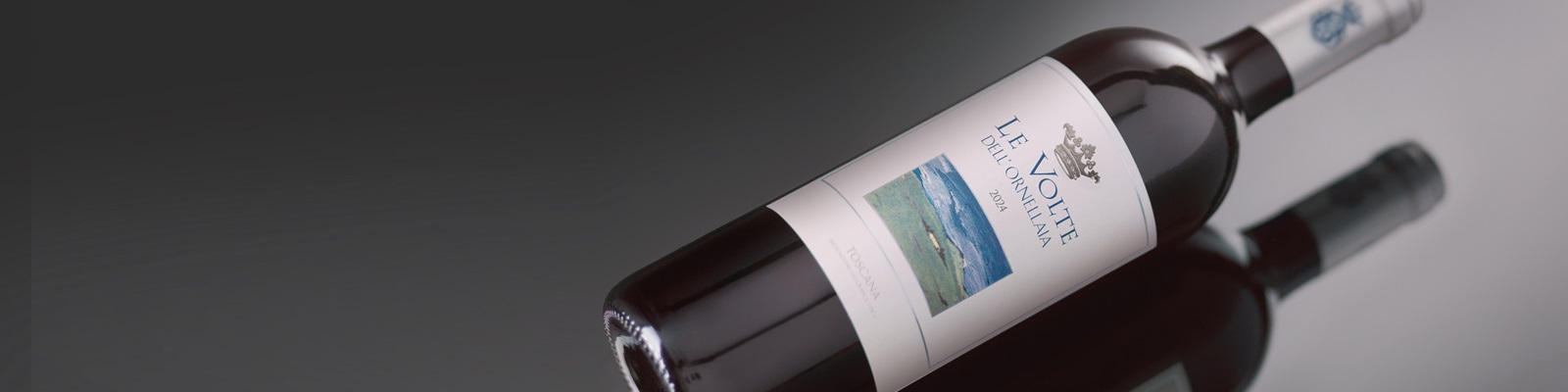 Eine Weinflasche mit einem eleganten Label liegt schräg auf einer reflektierenden Oberfläche. Das Etikett zeigt eine Landschaft und den Jahrgang 2014, umgeben von einem dunkelgrauen Hintergrund.