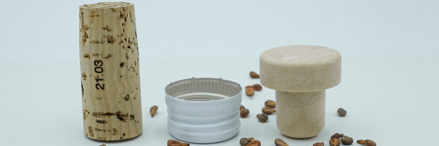 Weinflaschen liegen neben einem gefüllten Weinglas, das von einer Hand gehalten wird. Im Hintergrund sind ein Korkenzieher und Holzoberflächen zu sehen, die eine gemütliche Atmosphäre schaffen.