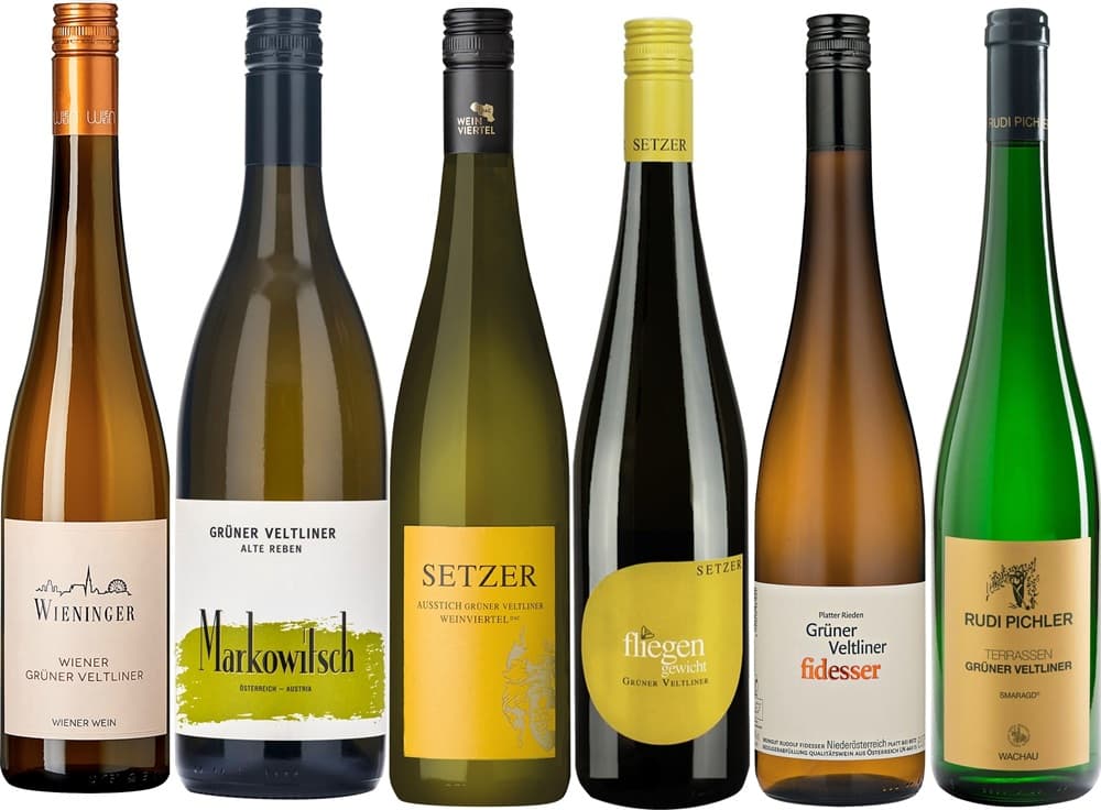 Weinpaket Grüner Veltliner Sechs Flaschen Weißwein stehen aufgereiht. Jede Flasche hat ein unterschiedliches Etikett, das die Weinsorte -Grüner Veltliner- bezeichnet. Die Flaschen variieren in Form und Farbe, einige sind transparent, andere grün oder braun.