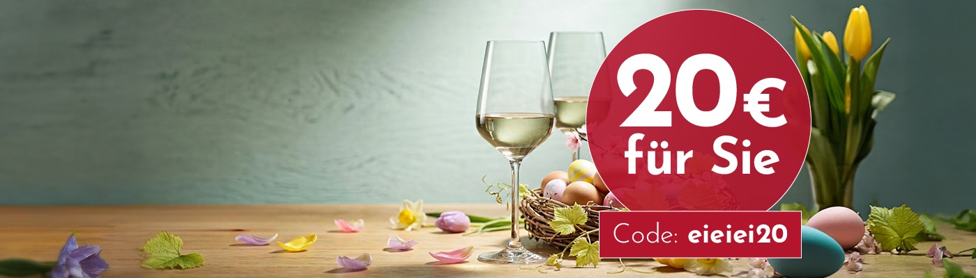 Zwei Gläser Weißwein stehen auf einem Holztisch, umgeben von bunten Ostereiern und Frühlingsblumen. Im Hintergrund sind tulpenartige Pflanzen zu sehen. Ein rotes Etikett sagt -20 € für Sie- und -Code: eiei20-.
