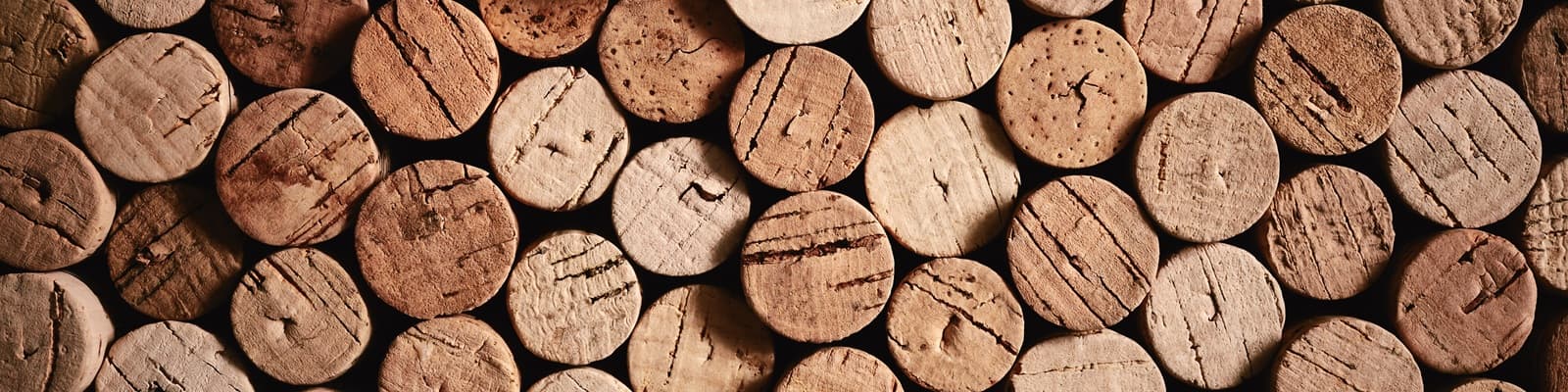 Korken liegen nebeneinander, einige mit Jahreszahlen wie 2003, 2007, 2008 und 2009 markiert. Die Korken sind aus hellem Material und haben eine griffige Textur.