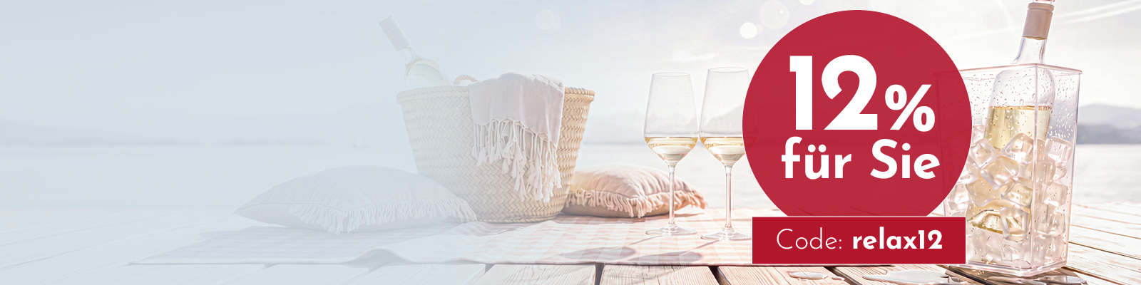 Gläser mit Getränk und eine Flasche stehen neben einem Korb auf einer Decke am Strand. Ein Rabattangebot von 12 % sowie ein Gutscheincode sind hervorgehoben.