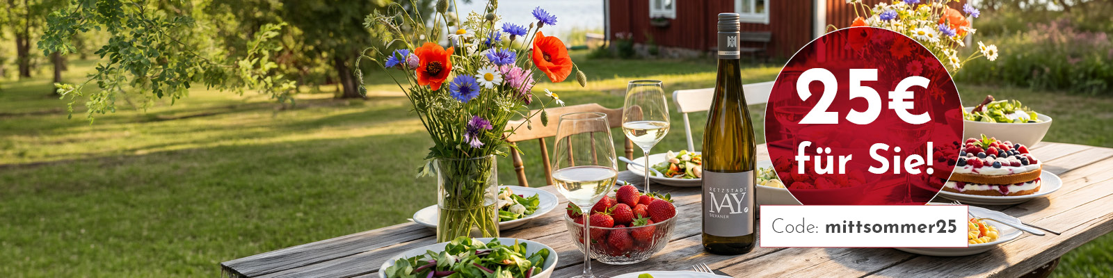 Ein festlich gedeckter Tisch im Freien mit Wein, Gläsern, frischen Salaten, Erdbeeren und einer Torte. Im Hintergrund blühende Bäume und ein rotes Gebäude. Rabattangebot von 25 € und Aktionscode.