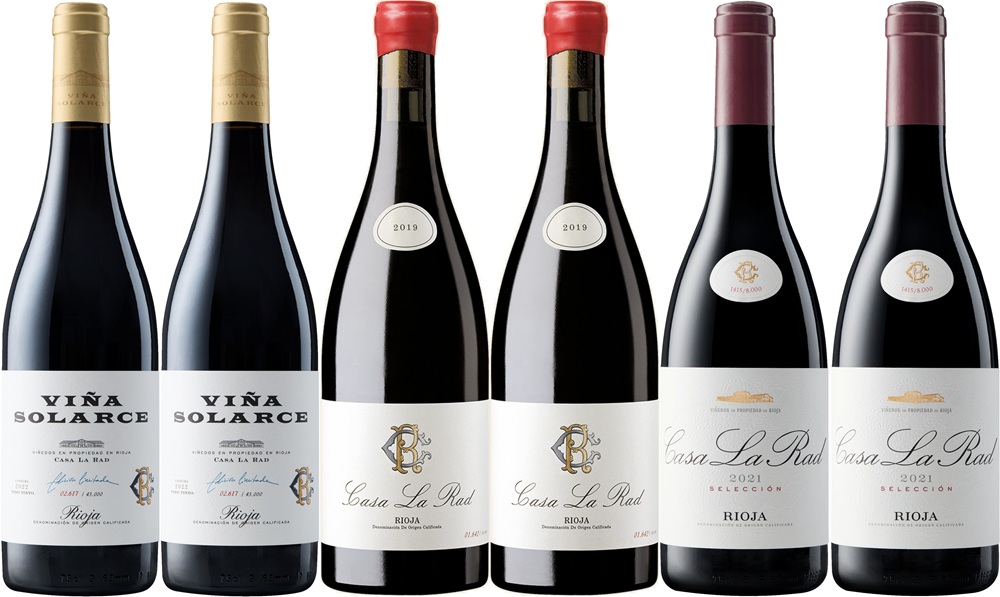 Sechs Flaschen Wein stehen in einer Reihe. Drei Flaschen tragen das Etikett -Viña Solarce-, drei weitere -Casa La Rad- mit unterschiedlichen Jahrgängen. Die Flaschen sind in verschiedenen Höhen, überwiegend rot.