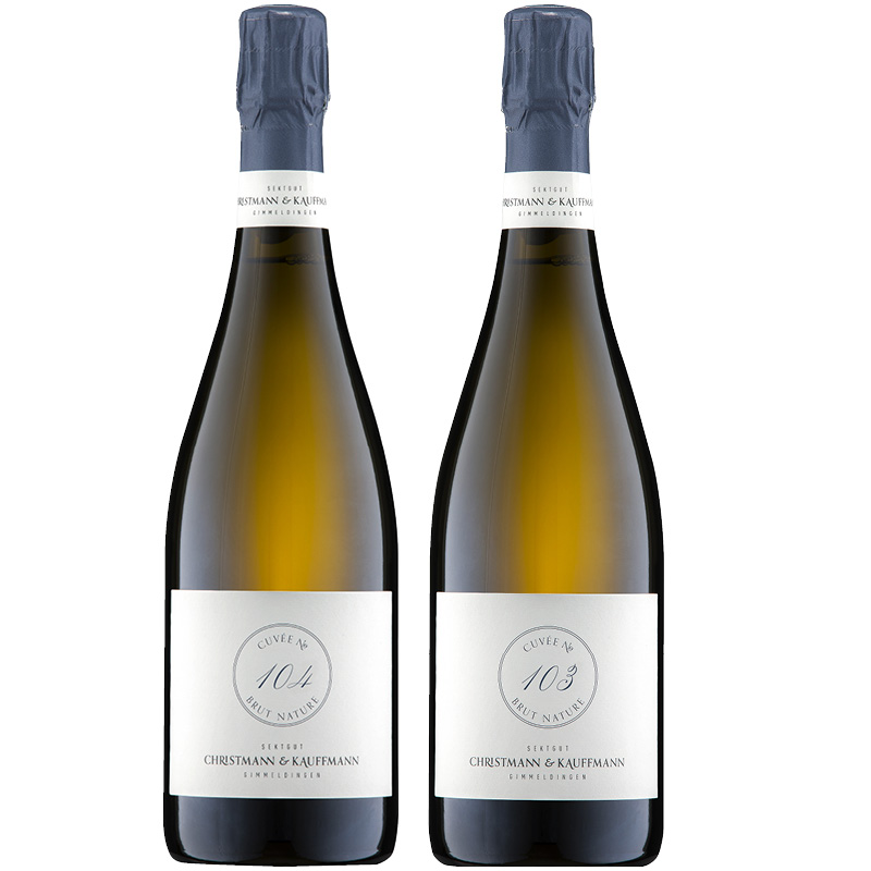 Christmann & Kauffmann Cuvée 103 & 104 Zwei Flaschen Sekt stehen nebeneinander. Beide haben eine helle, schlanke Form mit blauen Kappen und einem Etikett, das die Cuvées 104 und 103 zeigt.