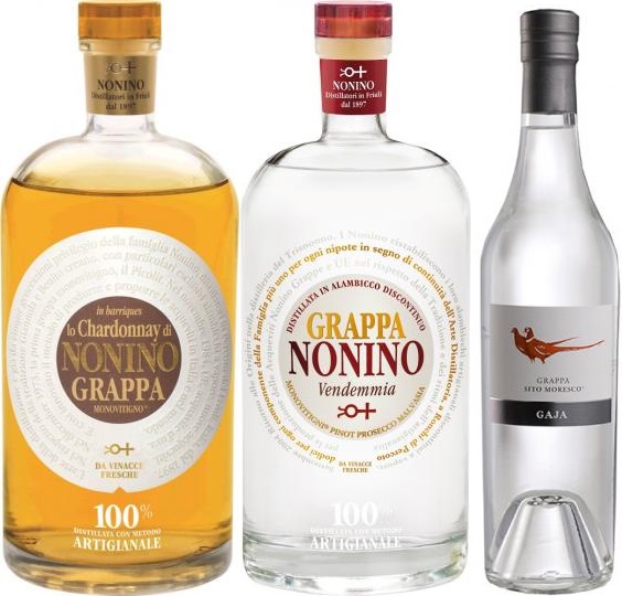 Grappa Topseller Vorteilspaket Drei Flaschen Grappa in unterschiedlichen Farben stehen nebeneinander. Links eine bernsteinfarbene Flasche, in der Mitte eine klare Flasche mit einer roten Kappe und rechts eine klare Flasche mit einem grauen Etikett.