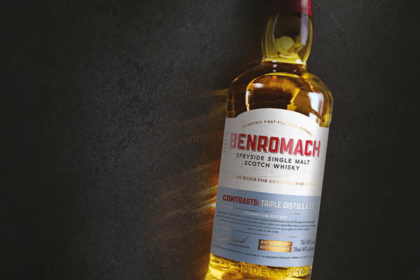 SDM_November_04 Eine Flasche Benromach Speyside Single Malt Scotch Whisky steht auf einer dunklen Oberfläche. Der Whisky hat eine goldene Farbe und das Etikett zeigt Informationen über die Abfüllung.