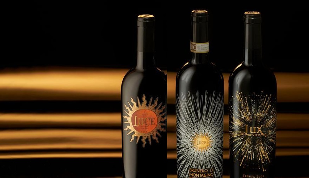 Drei edle Weinflaschen stehen vor einem dunklen, schimmernden Hintergrund. Die Flaschen haben auffällige Etiketten mit verschiedenen Designs und Farben, die Luxus und Eleganz ausstrahlen.