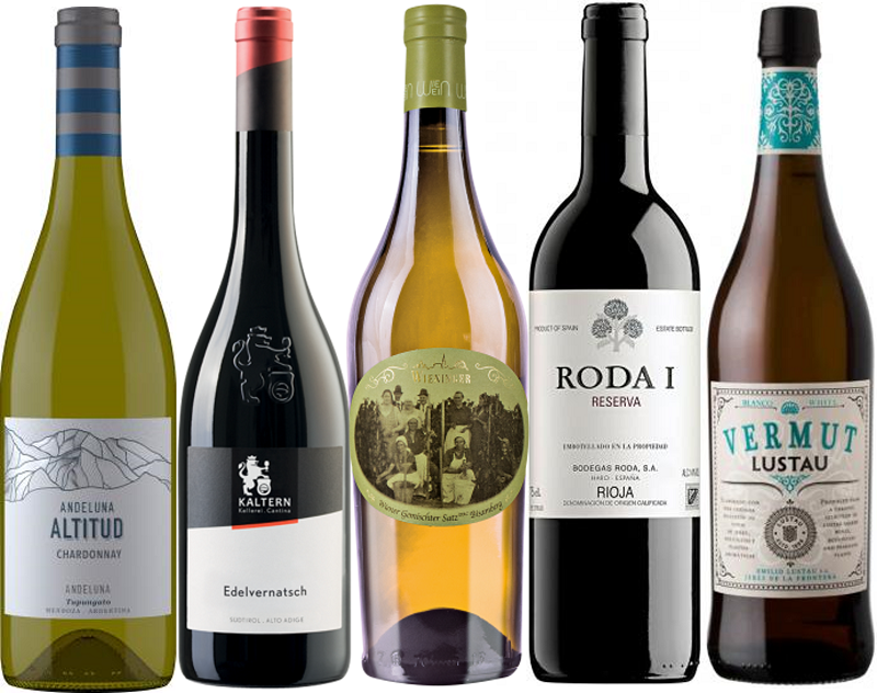 KOLLEGIUMs-Paket Frühlingserwachen Fünf Weinflaschen stehen nebeneinander. Sie sind unterschiedlich gestaltet: eine grüne Chardonnay-Flasche, zwei rote Weine, eine gelbe und eine weiße mit speziellen Etiketten.