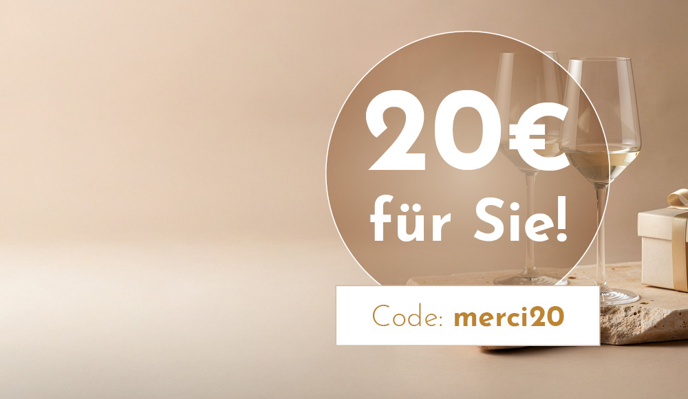 Zwei Weingläser stehen auf einem hellen Untergrund neben einem Geschenkpaket. Textankündigung: -20€ für Sie! Code: merci20-.